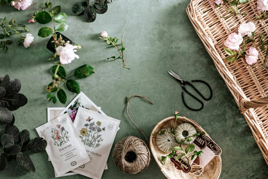 Flat lay of garden tools, seed packets, and flowers on green background, perfect for gardening themes.